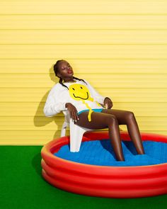 a woman sitting on top of an inflatable chair next to a yellow wall