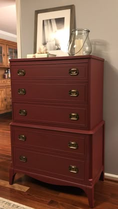 a red chest of drawers sitting on top of a hard wood floor