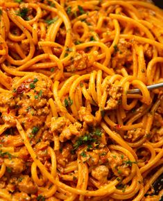 spaghetti with meat sauce and parsley is being stirred by tongs in a skillet