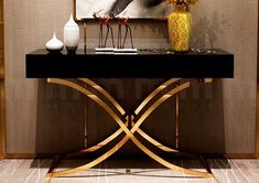 a black and gold console table with vases, flowers and pictures on the wall