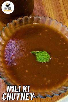 there is a bowl of soup with a green leaf on the table next to it