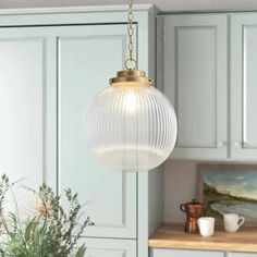 a light fixture hanging from the ceiling in a kitchen with green cabinets and white walls