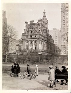 an old black and white photo of people on bicycles in front of a large building