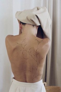 the back of a woman wearing a white dress with flowers drawn on it's back