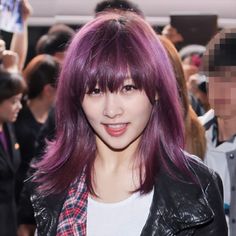 a woman with purple hair and black leather jacket in front of a group of people