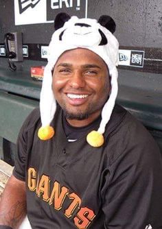 a baseball player wearing a panda hat sitting in the dugout