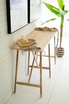 a wooden table sitting next to a plant on top of a hard wood floor covered in white tile