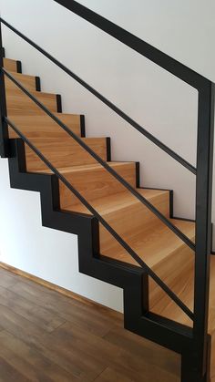 a wooden stair case with black handrails in a home setting on hard wood flooring