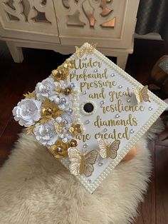 a white graduation cap decorated with gold and silver flowers