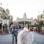 a bride and groom are walking down the street in front of disney's castle