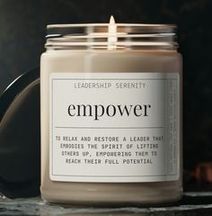 a candle that is on top of a table next to a black container with the words empover printed on it