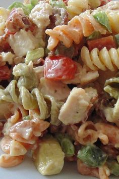 pasta salad with chicken, tomatoes, and other vegetables on a white plate close up