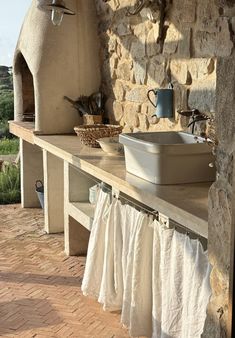 an outdoor kitchen with stone oven and sink on the outside wall, next to brick patio