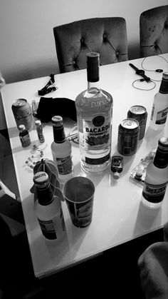 several bottles of alcohol sitting on a table in front of two chairs and a mirror