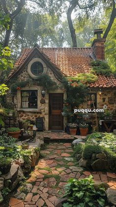 a small stone house surrounded by greenery and potted plants in the front yard