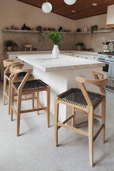 a kitchen with white counter tops and wooden chairs