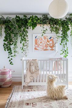 a white crib with plants on the wall and a sheep rug in front of it