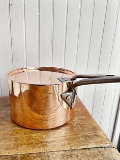 an old wooden table with a pot and tongs on it