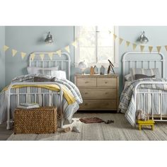 two beds in a room with blue walls and yellow flags on the wall above them