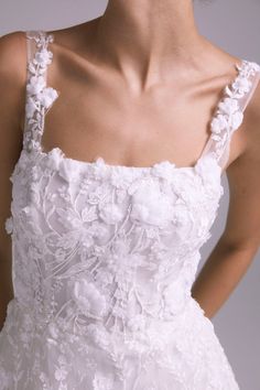 a woman in a white wedding dress with flowers on the boudon and straps