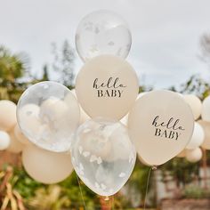 balloons with the words hello baby written on them are in front of some trees and bushes