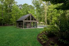 a small house in the middle of a lush green yard with trees and lawn chairs