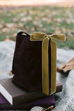 a brown bag sitting on top of two books with a ribbon tied around the book