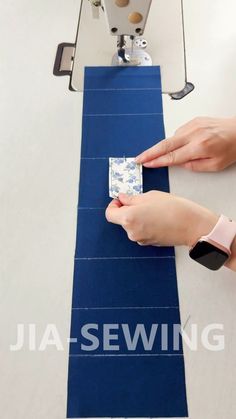 a woman is using a sewing machine to sew something on a piece of blue fabric