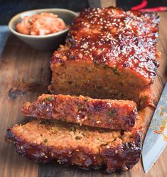 sliced meatloaf on cutting board with bowl of sauce