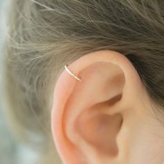 a woman's ear with a single diamond ring on it