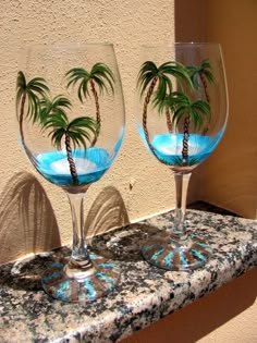 two wine glasses with palm trees in them