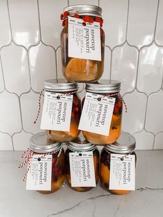 six jars of pickled fruit are stacked on top of each other in front of a tiled wall