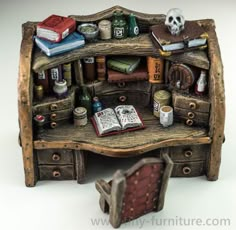 a miniature desk with books and other items on the top, sitting next to an open book