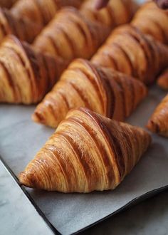 several croissants are lined up on a baking sheet and ready to be baked