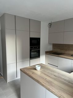 an empty kitchen with white cabinets and wood counter tops, is shown in this image