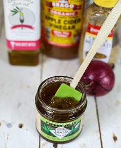 a jar of jam with a wooden spoon in it next to some spices and other condiments