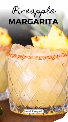 two glasses filled with pineapple margarita on top of a wooden table