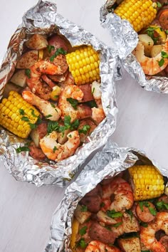 three foil packets filled with shrimp and corn on the cob