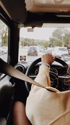 a woman driving a car with her hand on the steering wheel