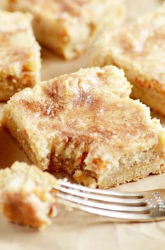 a close up of some food on a plate with a fork near it and another piece of cake in the background