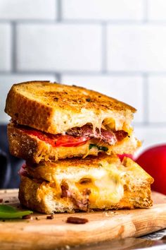 two grilled cheese sandwiches stacked on top of each other with an apple in the background