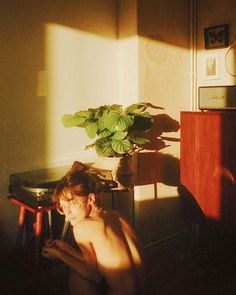 a naked woman sitting in front of a table with a potted plant on it