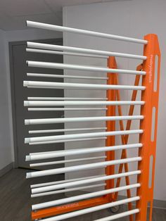 an orange and white rack with several poles attached to the wall next to each other