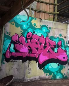 graffiti on the side of a building with blue and pink spray paint in front of it