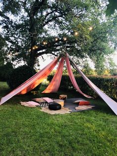 a tent set up in the grass with lights hanging from it