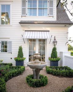 a white house with a fountain in the front yard