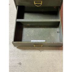 an old metal box with two drawers on top and one drawer open to show the contents