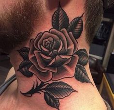 a man's neck with a black rose tattoo on the top of his neck