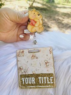 a person holding a winnie the pooh badge with glitter on it's side