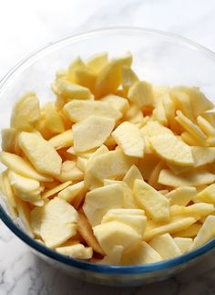 a glass bowl filled with sliced apples on top of a table